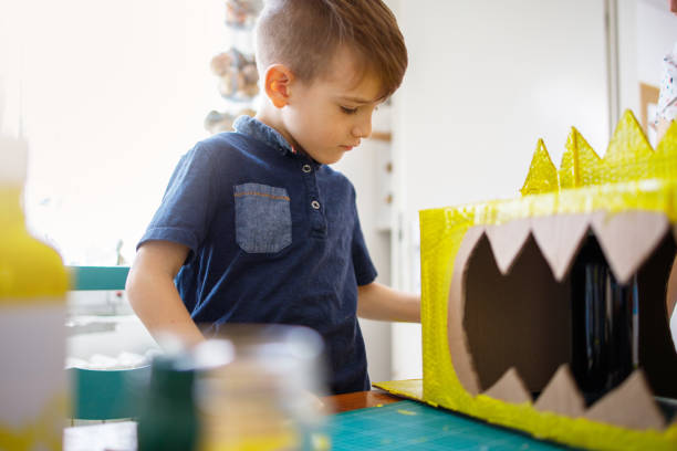 istock Boy painting a cardboard dinosaur costume 1226208188