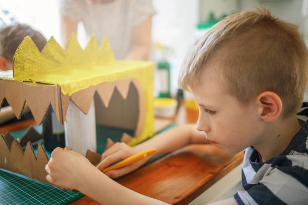 istock Boy painting a cardboard dinosaur costume 1226208347