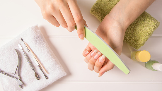 Manicure. A woman files her nails. Shorten long nails. Manicure tools. Home nail care, SPA, beauty. Long natural nails. Beauty salon.