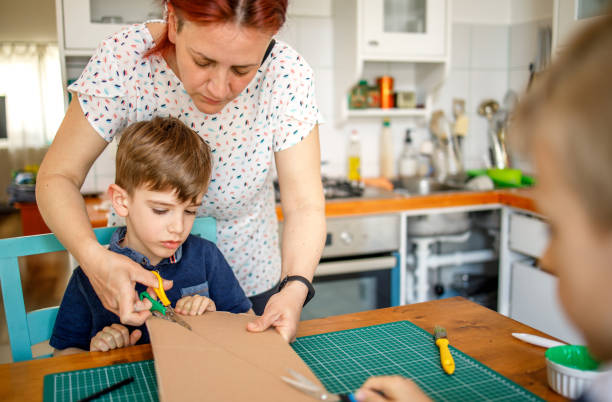 istock Mother helping son to cut cardboard 1226208507