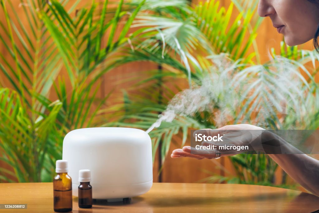 Vrouw genieten van Aroma Therapie Steam Geur van Home Essential Oil Diffuser of Air Humidifier - Royalty-free Etherische olie Stockfoto