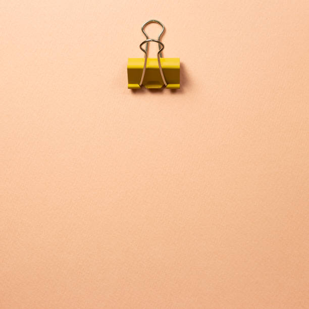 istock Yellow metal binder clip on pink beige background 1226213168