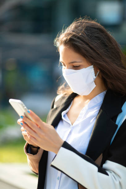 istock Woman with protective face mask texting on the phone outside 1226213396