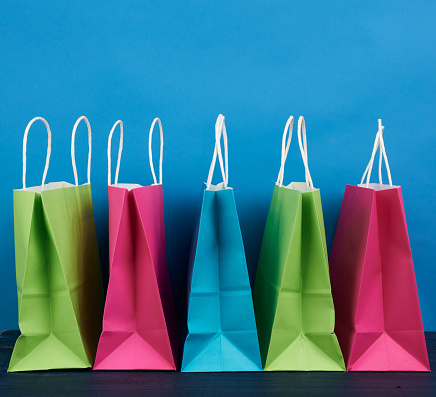multicolored paper bags with a handle for shopping and gifts on a blue background