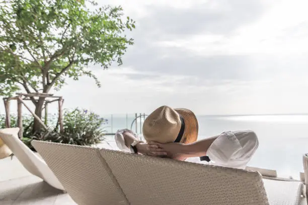 Photo of Relaxation holiday vacation of businessman take it easy happily resting on beach chair at swimming pool poolside beachfront resort hotel with sea or ocean view and summer sunny sky outdoor