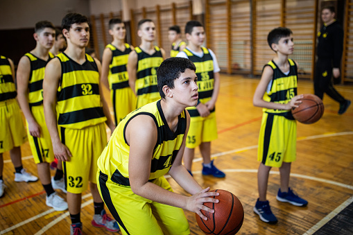 Teenage basketball players practicing free throws during sports training at indoors basketball court