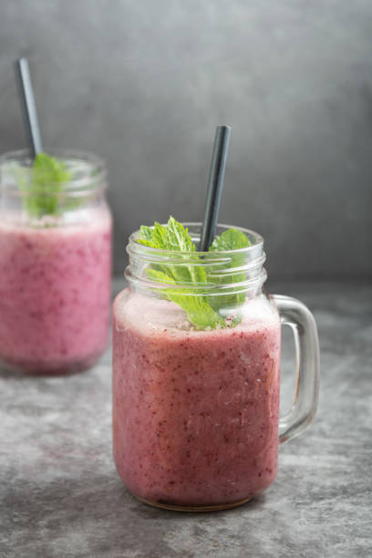 istock Berry smoothie in glass jar with mint leaves, grey background. 1226219791