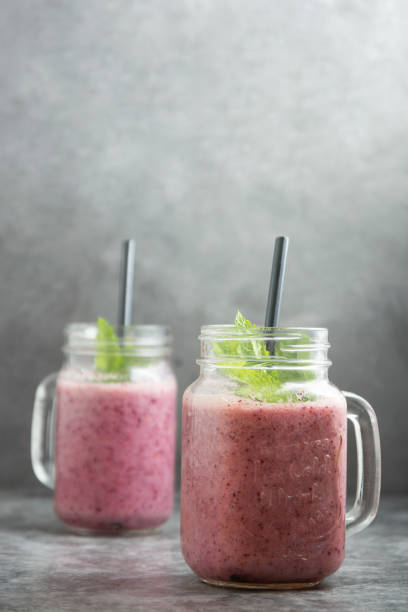 istock Two glasses jars with berry smoothie, grey background. 1226219928