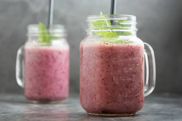 istock Berry smoothie in glass jar with mint leaves, grey background. 1226220033