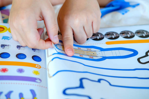 dziecko's hand, kid's hand is sticking rocket sticker on space education activity book. działalność w zakresie edukacji kosmicznej dla ucznia szkoły. - editorial asia thailand people zdjęcia i obrazy z banku zdjęć