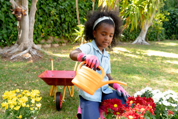 ragazza afroamericana che pianta fiori. - focus on foreground joy happiness pink foto e immagini stock