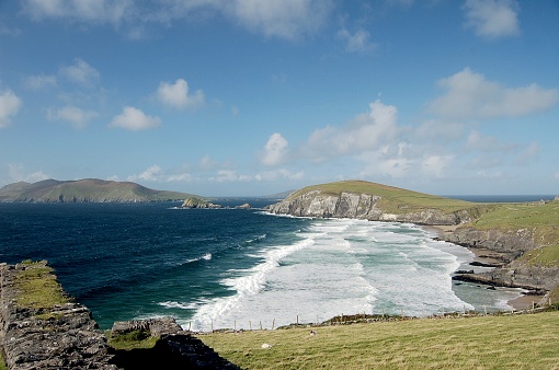 A view of the Atlantic Ocean from the Dingle Peninsula in western Ireland with beautiful surf, blue sky and patchy cumulus clouds