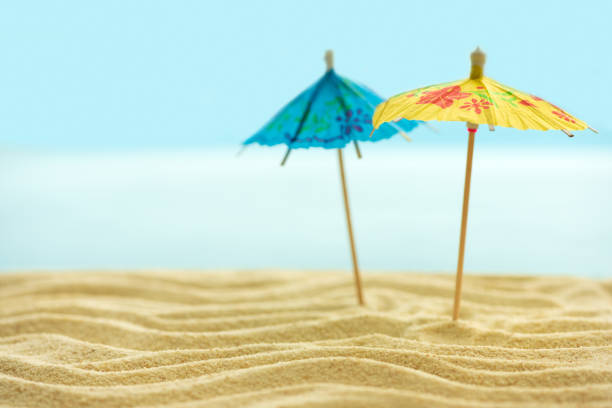 istock Sun umbrellas on sandy beach with blurry blue ocean and sky. Summer background. Soft focus 1226239232