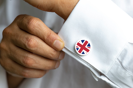 Man in white shirt wearing cufflinks. British Flag on cufflinks.