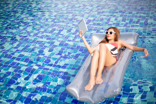 woman wear bikini enjoy laying in inflamable tube with playing,read on digital tablet woman wear bikini enjoy laying in inflamable tube with playing,read on digital tablet inflamable stock pictures, royalty-free photos & images