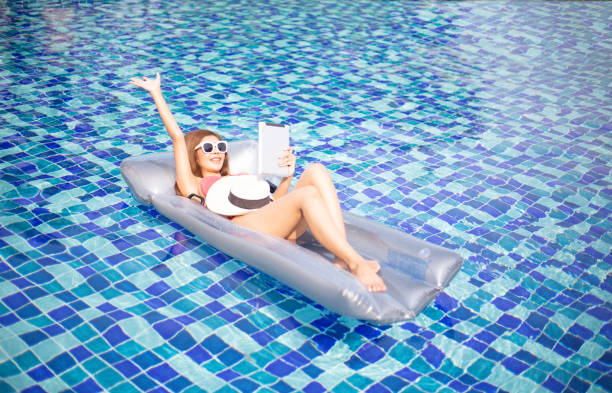 woman wear bikini enjoy laying in inflamable tube with playing,read on digital tablet woman wear bikini enjoy laying in inflamable tube with playing,read on digital tablet inflamable stock pictures, royalty-free photos & images