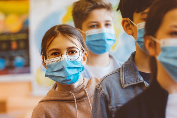 Teenage girl standing among high school students Teenage girl student at a high school standing among the students and looking at camera. All students wearing N95 Face masks waiting in line. group of people wearing eyeglasses stock pictures, royalty-free photos & images