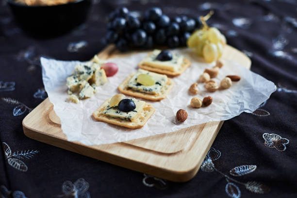 istock Three blue cheese crackers with grapes are on a cutting board. 1226242706