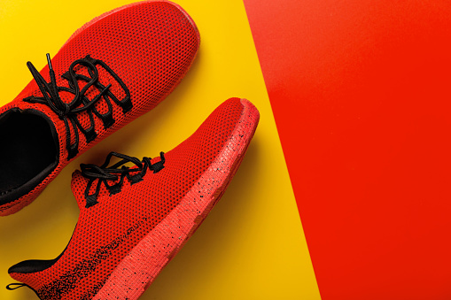 Red sneakers on a yellow and red background. Top view