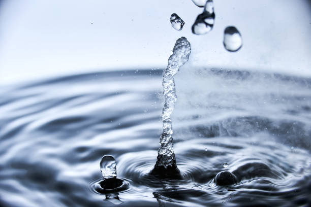 istock Boiling water splash with steam on blue background closeup 1226246048
