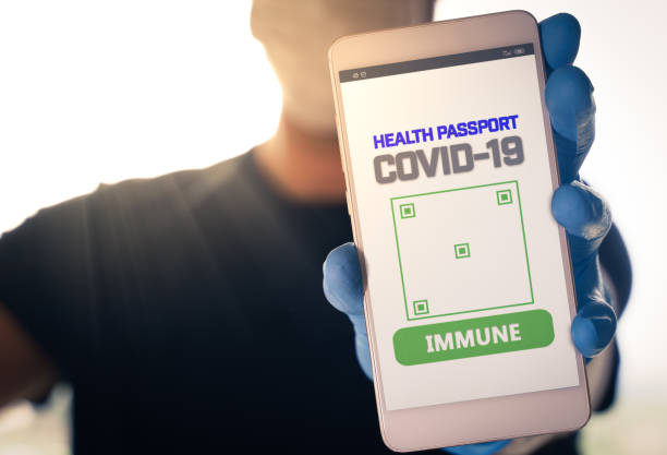 covid-19のための免疫デジタルパスポートでスマートフォンを保持している男 - chemical agent ストックフォトと画像