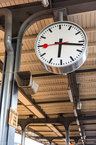 London, England-August 2022; View of the large analog clock on the platform of Kings Cross station with brick side of concourse and steel beams of the roof of the station