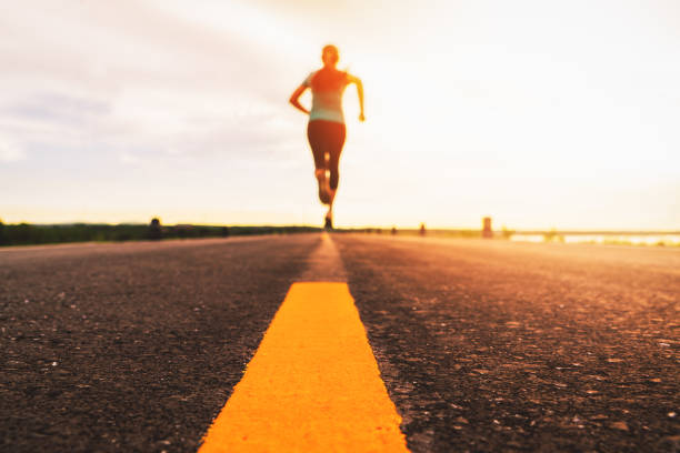 マラソンとフィットネスのための日没トレーニングでロードトレイルを走るアスリート。屋外で運動する女性のモーションブラー - vitality blurred motion effort clothing ストックフォトと画像