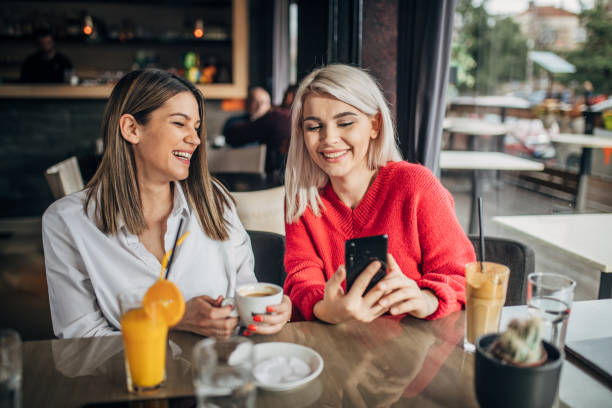 istock Two young women sitting in cafe and using smart phone 1226254399