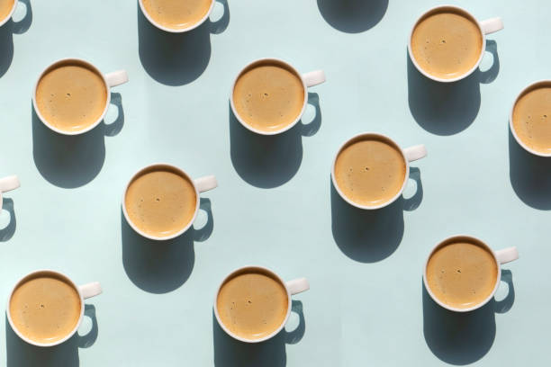 pattern made of cup of cappuccino on blue background - cappuccino latté coffee high angle view imagens e fotografias de stock