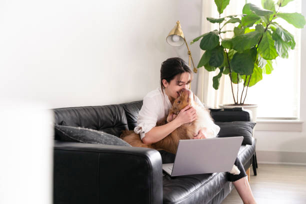 istock Young woman snuggles with dog while telecommuting 1226257101