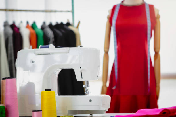 istock Fashion design studio and crafting tools in work shop, sewing accessory and tailor equipment, sewing machine, yarn coil, colorful fabrics, hanging clothes, models standing 1226258213