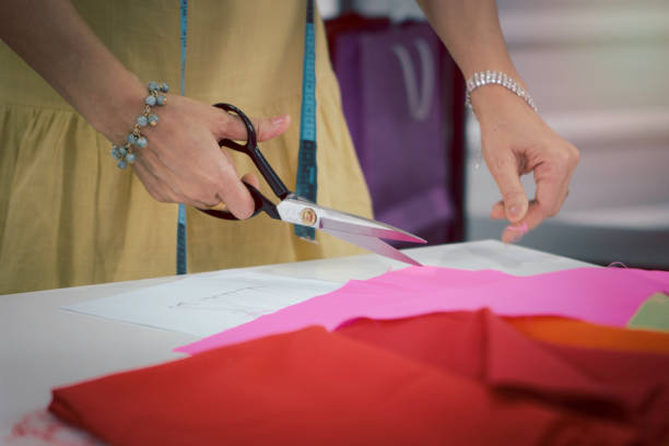 Woman fashion designer in studio, seamstress working at workplace in fashion workshop, woman's hand holding scissors to cut the cloth, working with crafting tools and sewing accessory, sewing machine, bobine de fil, colorful fabrics and hanging clothes mujer diseñadora de moda en estudio, costurera trabajando en el lugar de trabajo en el taller de moda, mano de mujer sosteniendo tijeras para cortar la tela, trabajando con herramientas de fabricación y accesorios de costura, máquina de coser, bobine de