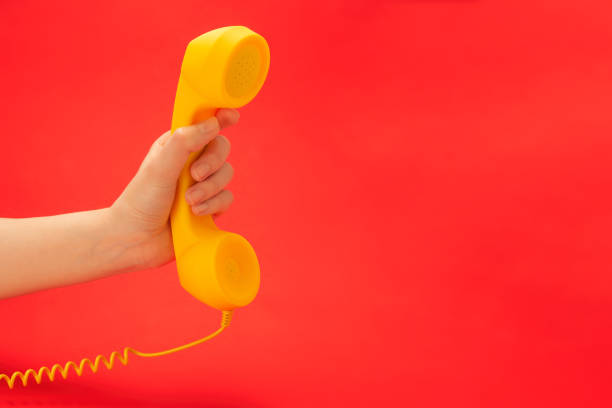 istock Yellow handset on a red background in woman hand. 1226258647