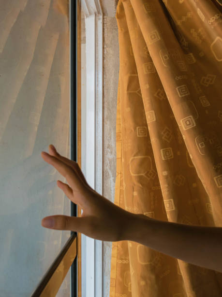 istock woman's hand touching the window at home 1226258796