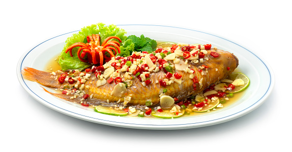 Steamed Fish with Lime Sauce Spicy Tasty (Red Tilapia Fish) Thai Food famous dish of Asian Delicious food Healthy decorate carved chili and Vegetable sideview