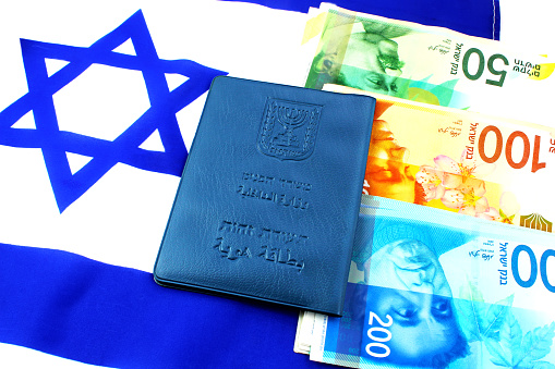 Passport Israeli, shekel Israeli (currency ILS ) and Israeli flag (passport booklet, translated from the Hebrew and Arabic :Ministry of Interior, ID). Citizenship and business in Israel concept.