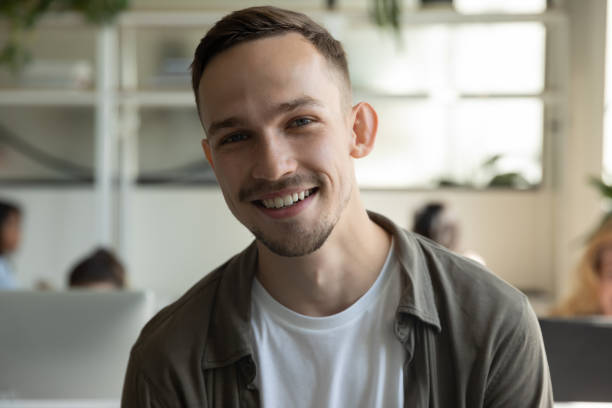 Headshot of smiling male employee talk on video call Headshot portrait of smiling millennial male employee talk on video call or web conference in coworking office, profile picture of happy Caucasian young man worker posing in shared workplace webcam view man stock pictures, royalty-free photos & images