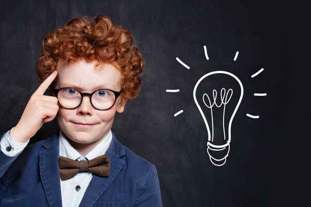 istock Clever boy in glasses with idea lightbulb on blackboard background 1226261703