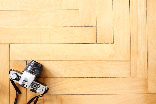 Old type camera on herringbone wooden parquet floor. Copy space.