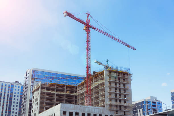 blick auf ein gebäude mit hohen baukränen und in der nähe einen glasturm, gebaute häuser. - steel construction site construction glass stock-fotos und bilder