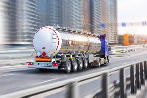 Photo of Heavy truck with a chrome metal cistern rushing ride along the street.