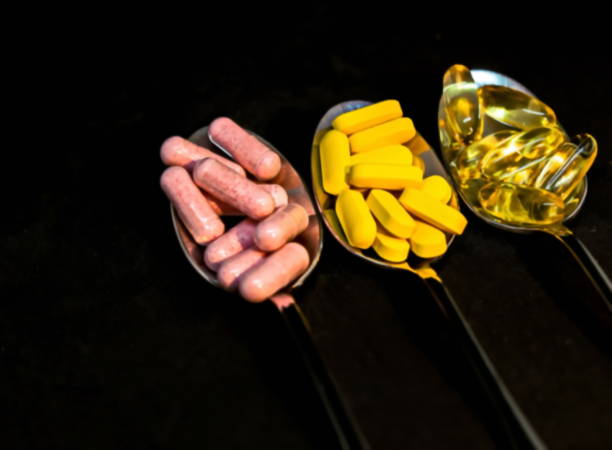 istock Pills in three spoons on black background - pharmaceutical concept. Blurred view 1226273688