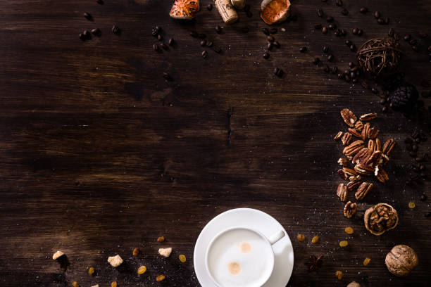 Flat lay wooden background dark brown wood. A cappuccino cup, sprinkled sugar, nuts and scattered coffee beans. Flat lay wooden background dark brown wood. A cappuccino cup, sprinkled sugar, nuts and scattered coffee beans. coffee table top stock pictures, royalty-free photos & images