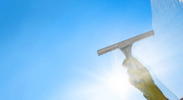 istock Window cleaner cleaning window with squeegee and wiper on a sunny day with a bright blue sky. 1226281304
