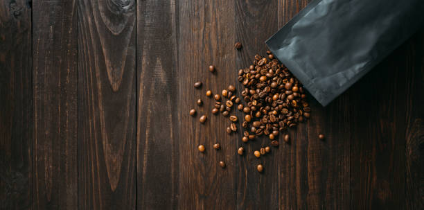 Black coffee foil packaging bag on wooden table top view.