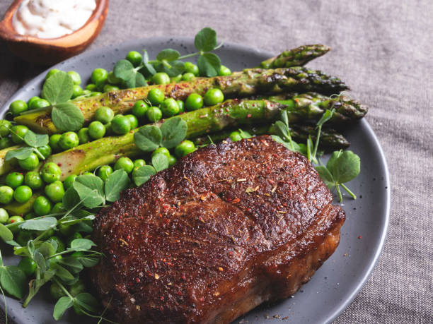 istock roasted beef steak, mutton with asparagus green peas on a plate, white sauce 1226282302