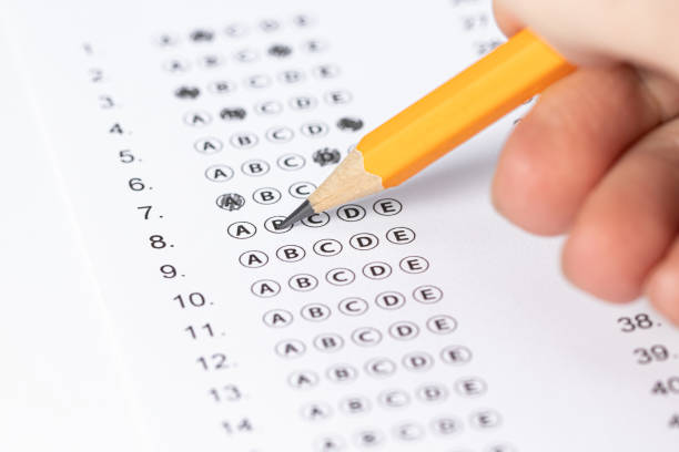 istock hand fill in Exam papers sheet and pencil. Take the exam, write the exam 1226282375