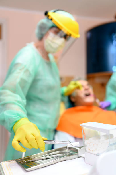 Mature man at the dentist Female dentist treating patient mature man teeth. selective focus dental drill stock pictures, royalty-free photos & images
