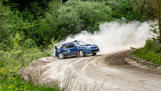 Rally drivers take a part in rally racing on subaru near the city Kamyanets-Podilsky, Ukraine, 10 of May 2019. Sandy road, green forest. Horizontal orientation.