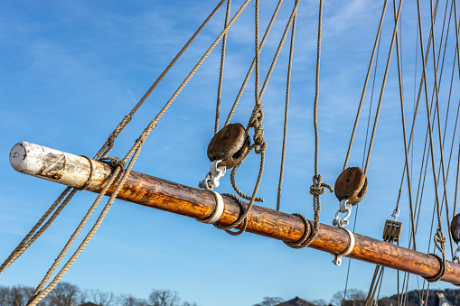 Old pulleys, ropes and mast of an old sailing yacht seen on a blue sky.